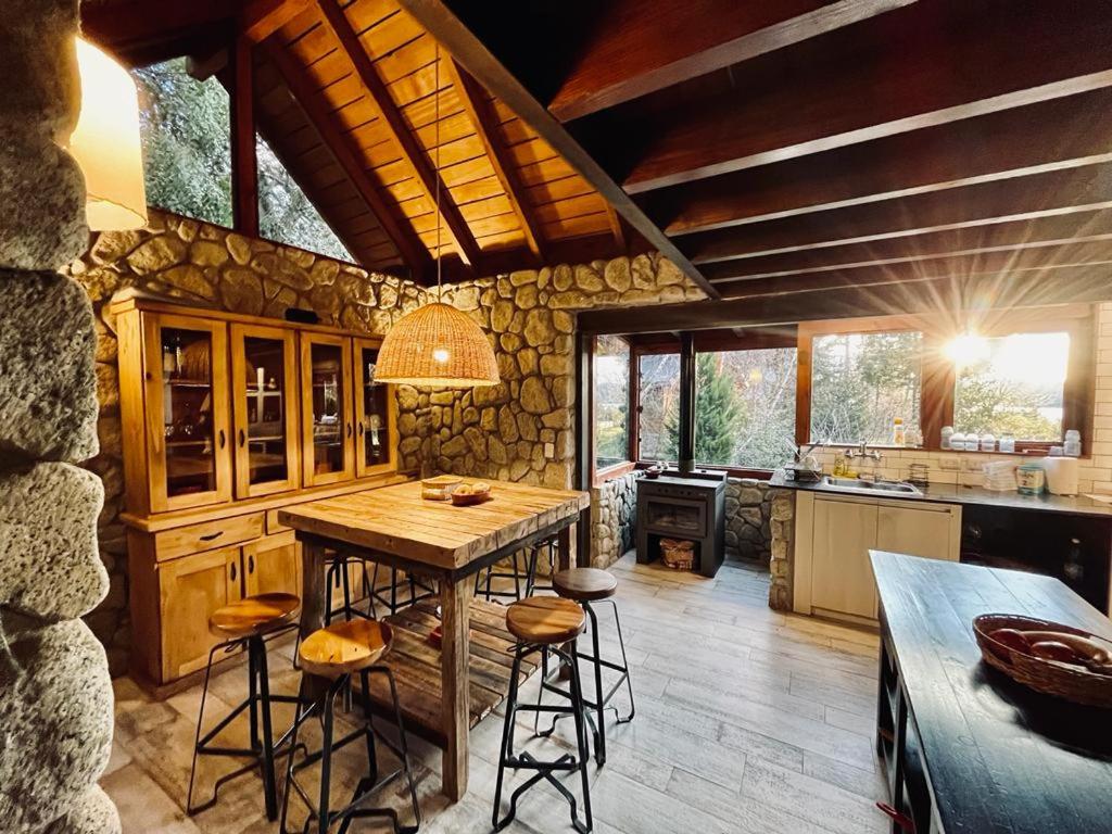 una cucina con tavolo in legno e alcuni sgabelli di Hogar de Montaña a Villa La Angostura