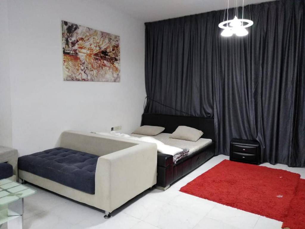 a bedroom with a bed and a couch and a red rug at Studio Apartment in Ajman 