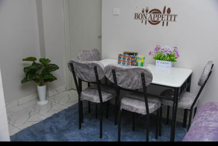 einen Esstisch mit 4 Stühlen und einem weißen Tisch in der Unterkunft Poly's Place Airbnb in Nairobi