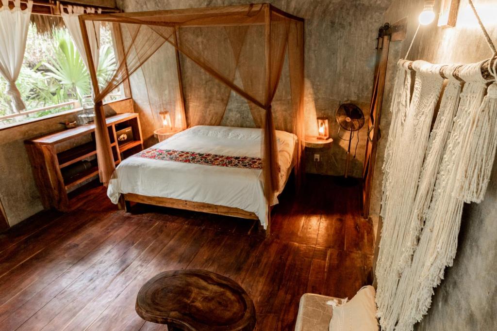 a bedroom with a canopy bed and a wooden floor at Aldea Colibri in Macario Gomez