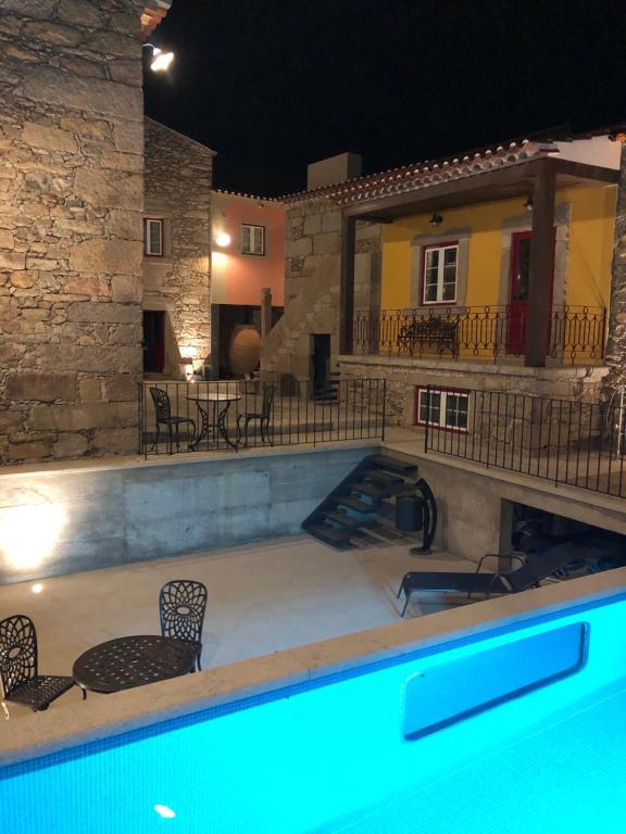 uma piscina com cadeiras e uma casa à noite em Casas do Solar - Guest House - em Almeida