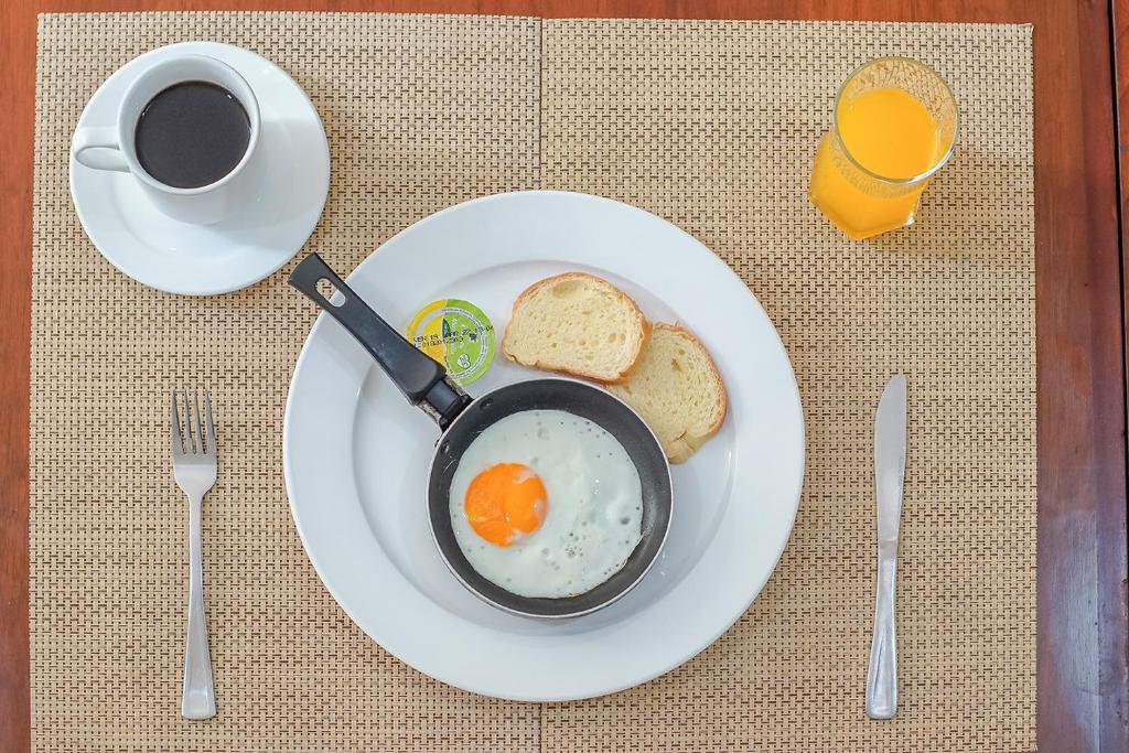 帕斯托的住宿－Ayenda Hotel Posada Leon，盘子,盘子上放着一碗鸡蛋和面包,还有一杯咖啡