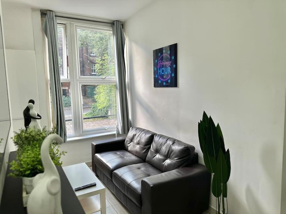 a living room with a black leather couch in front of a window at Clarendon Offers Perfect Contractors Home in Leeds