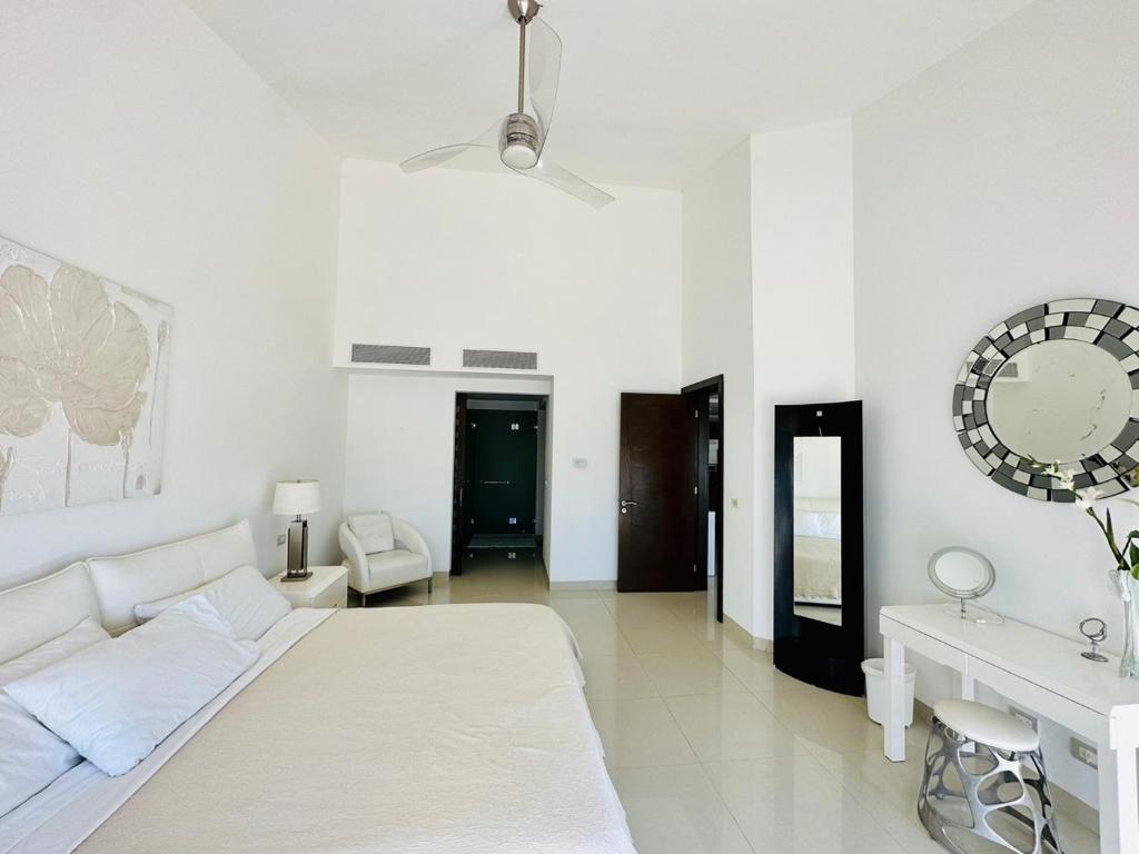 Dormitorio blanco con cama blanca y espejo en Luxury Beachfront Resort at MAREAZUL en Playa del Carmen