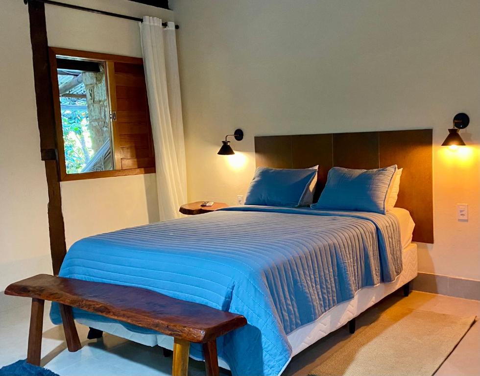 a bedroom with a large bed with blue sheets and a bench at Vila Verde Perto in Lençóis