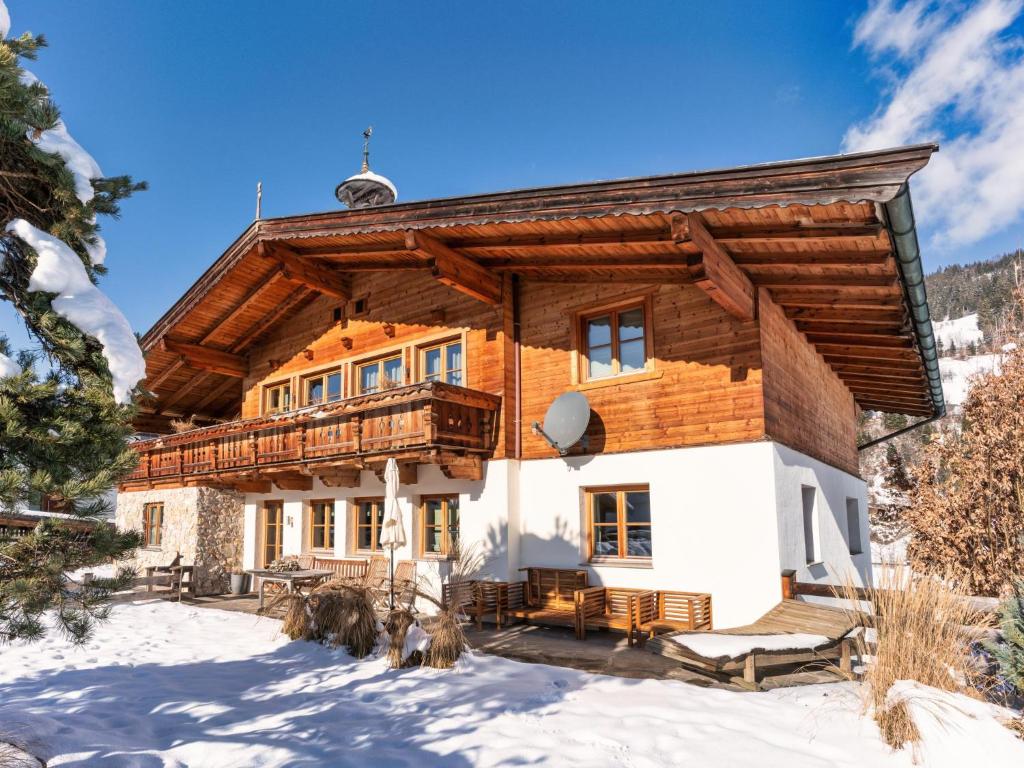 une cabane en rondins dans la neige avec un balcon dans l'établissement Chalet-Apartment Alpenrose am Lift, à Kirchberg in Tirol