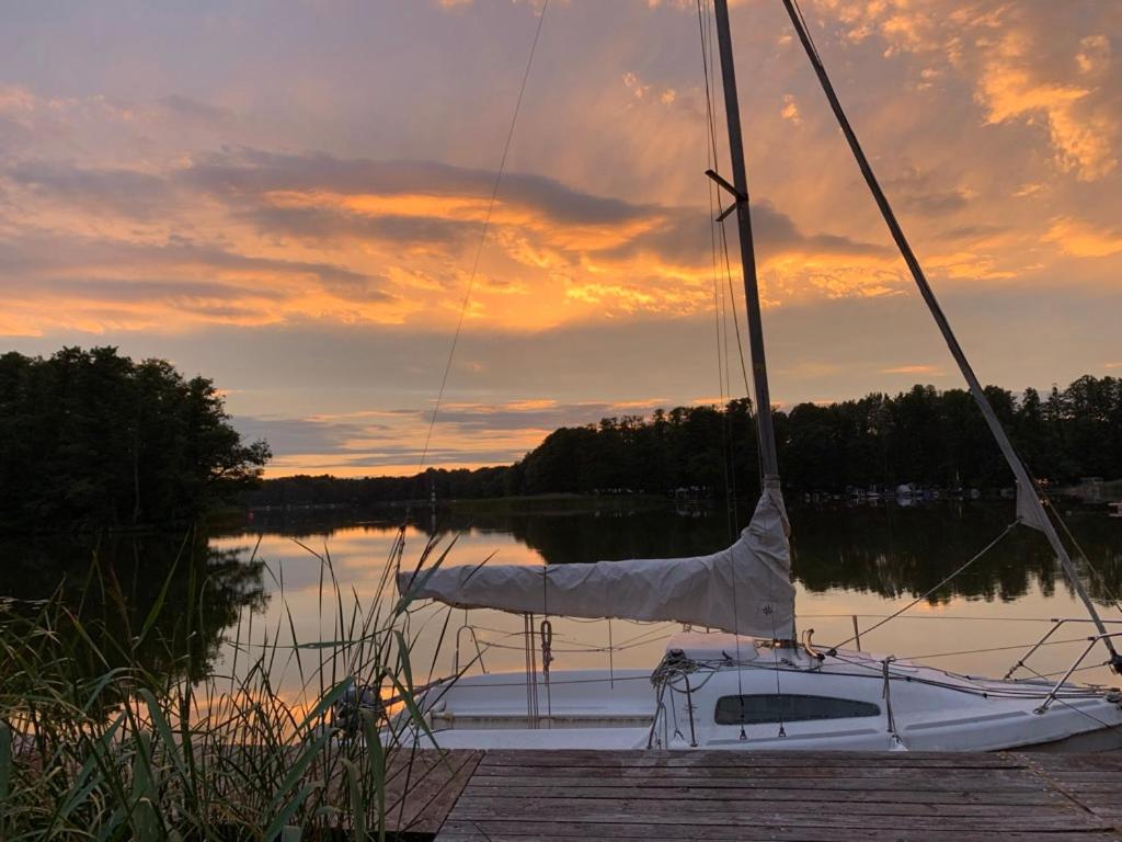 a sailboat sitting on a dock in a lake at sunset at La Bohème in Groß Köris