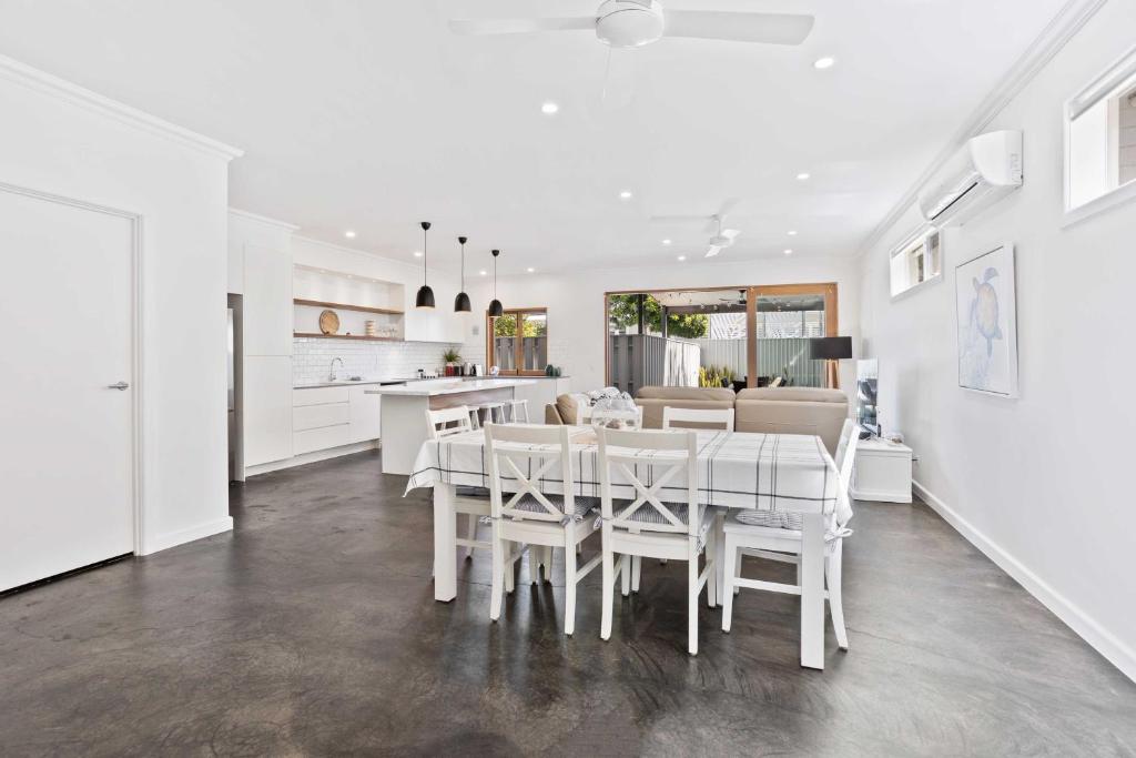 a white kitchen and dining room with a table and chairs at Perfect Palm Beach Townhouse - Hosted by Burleigh Letting in Gold Coast