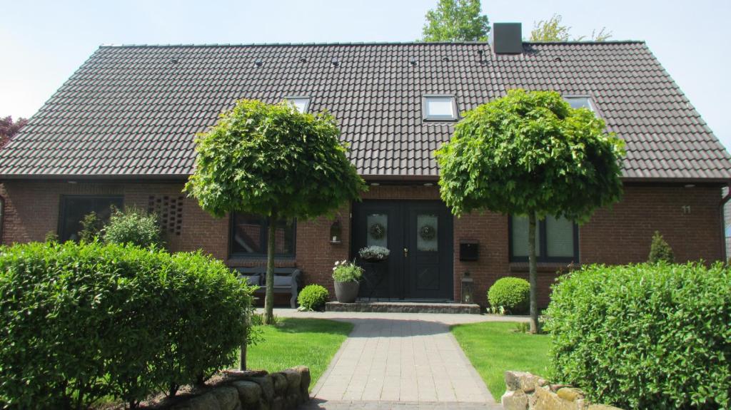 uma casa de tijolos com uma porta preta e duas árvores em Ferienwohnung Allegra em Süderlügum