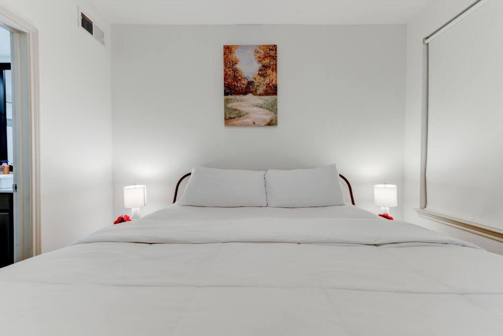 a white bed in a white bedroom with a picture on the wall at Serenity Haven SOCo2BR/2BA DTATX in Austin