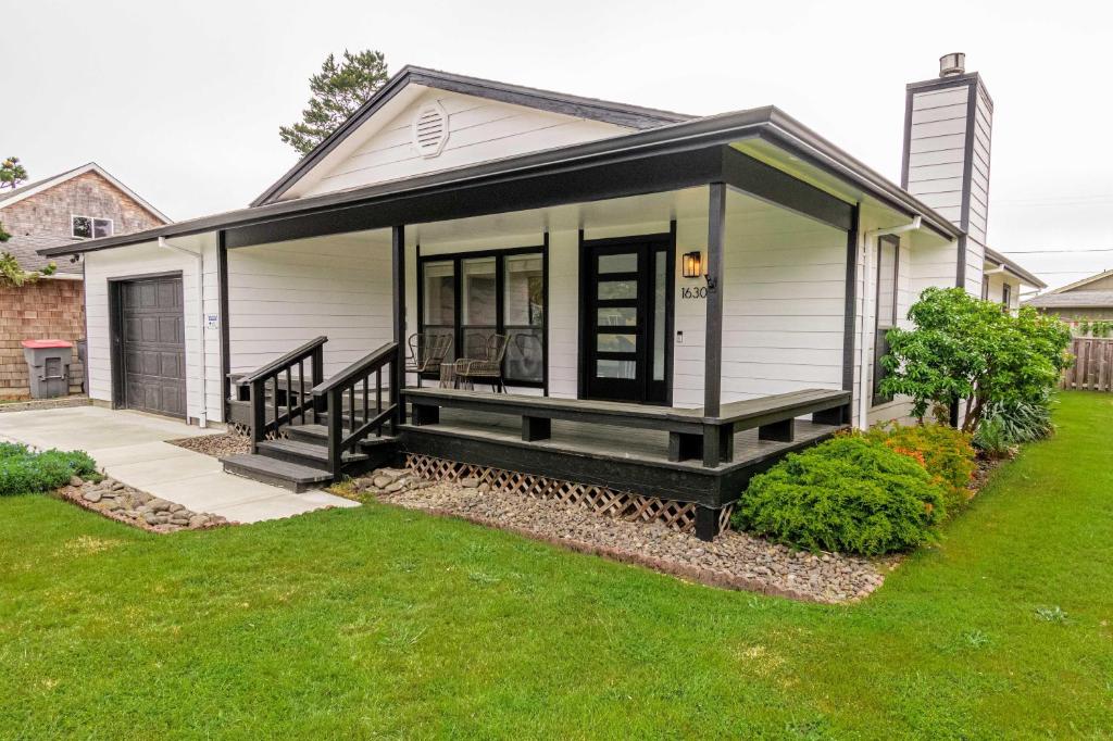 a tiny house with a porch and a lawn at Cozy Cove Cottage in Seaside