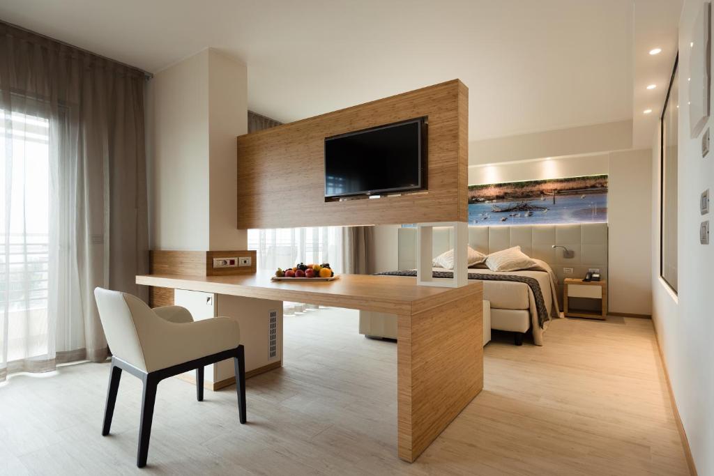 a living room with a desk and a bedroom at Laguna Park Hotel 4Superior in Bibione
