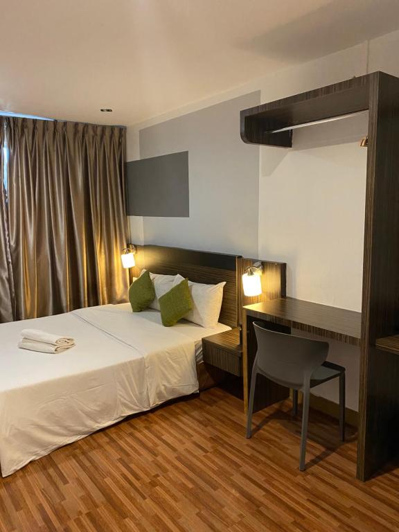 a bedroom with a bed and a desk with a chair at V Hotel Johor Bahru in Johor Bahru