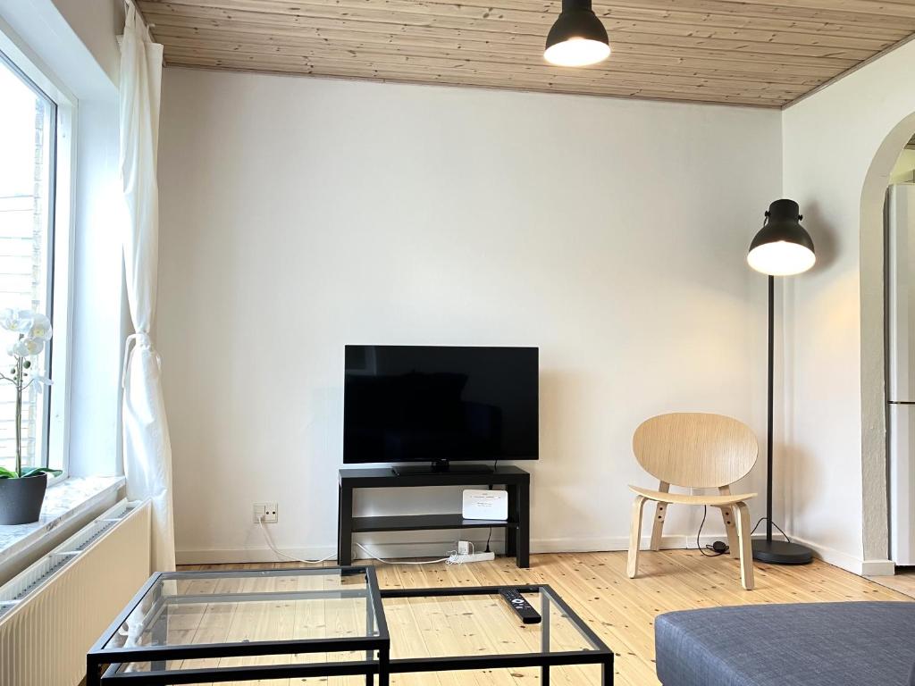 a living room with a tv and a glass table at Lovely Two Story House in Odense