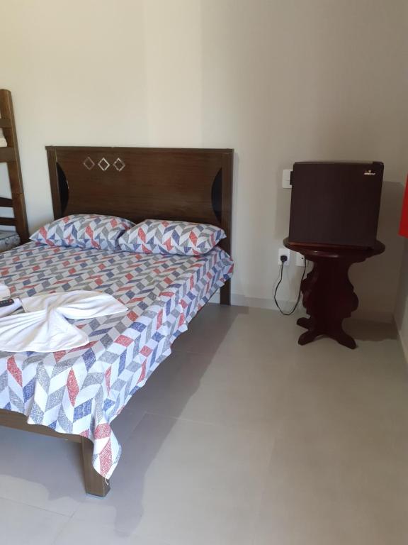 a bedroom with a bed and a flat screen tv at Chalés Bela Vista in Serra Negra
