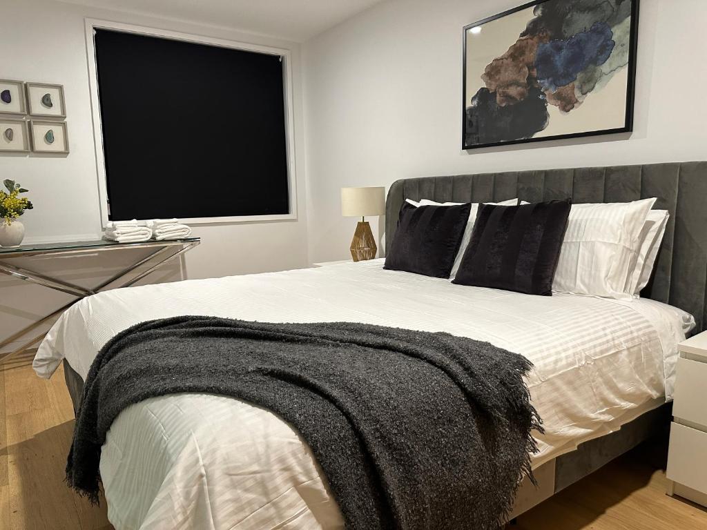 a bedroom with a bed with a black blanket on it at Palko - Stylish in the City in Canberra