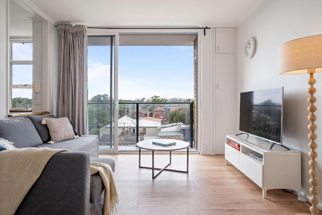 a living room with a couch and a large window at Cute 2 Bedroom Apartment Kensington in Sydney