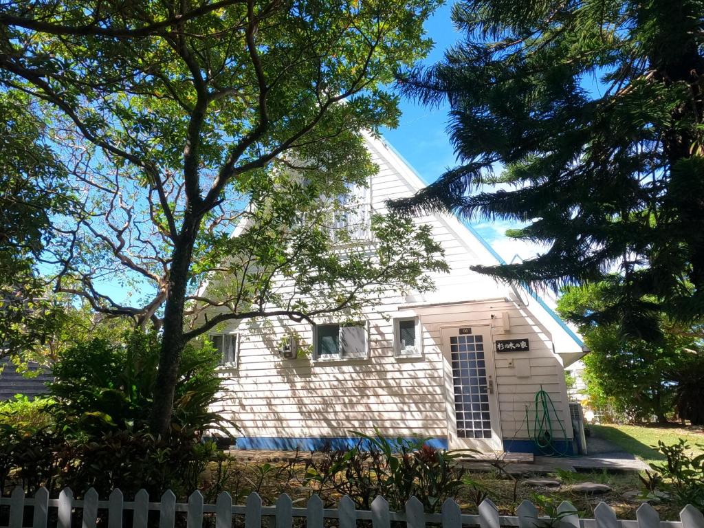 a white house behind a white fence at にらい恩納　杉の木 in Onna