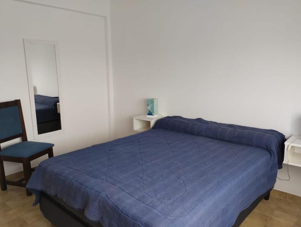 a bedroom with a blue bed and a chair at Bravard suites in Bahía Blanca