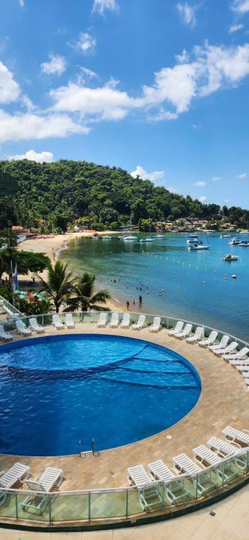 a swimming pool with lounge chairs and a beach at Angra inn - Angra dos Reis - apê120 in Angra dos Reis