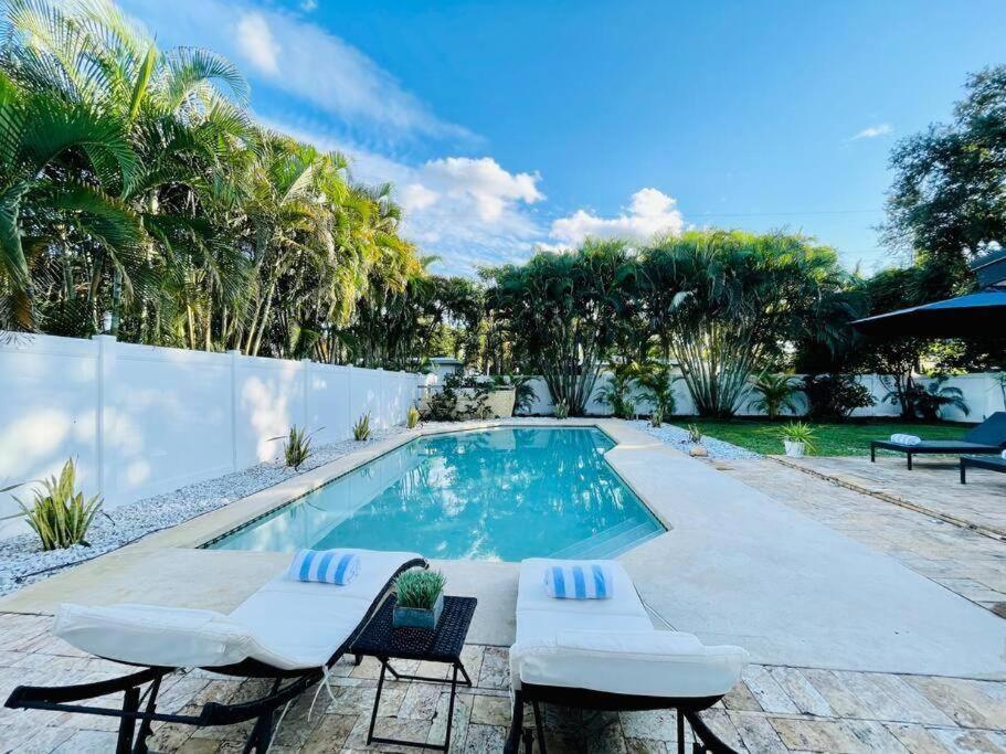 uma piscina com duas espreguiçadeiras ao lado de uma cerca em Tropical Oasis House Private Pool Family Yard em Fort Lauderdale