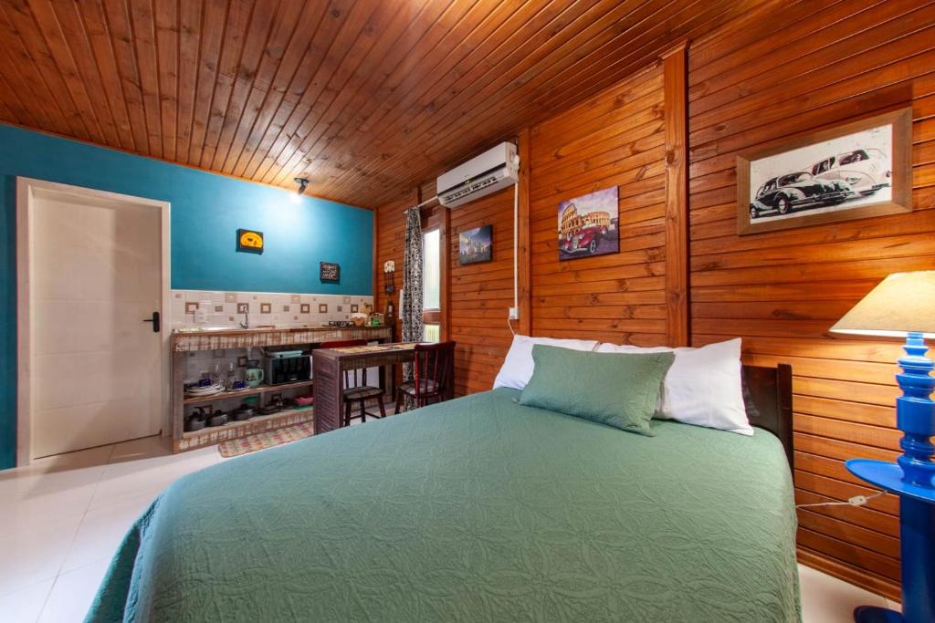 a bedroom with a green bed in a room with wooden walls at Casa Di Fiori in Apiúna