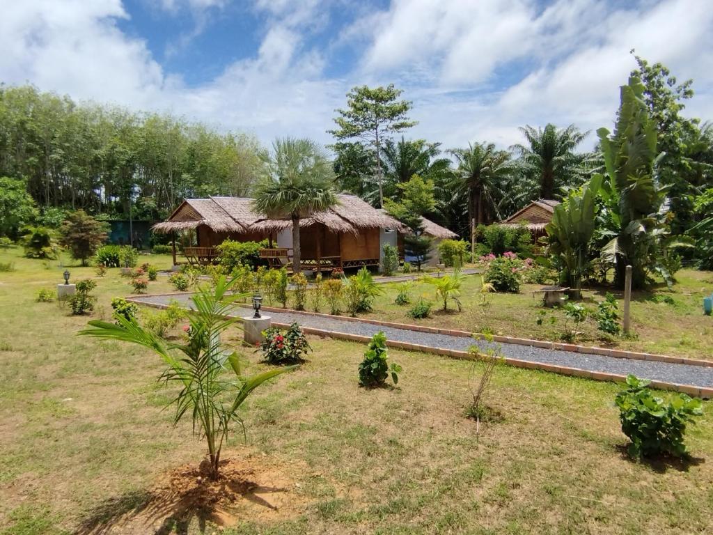 a garden with a house in the background at Palm Garden Bungalows in Ko Lanta