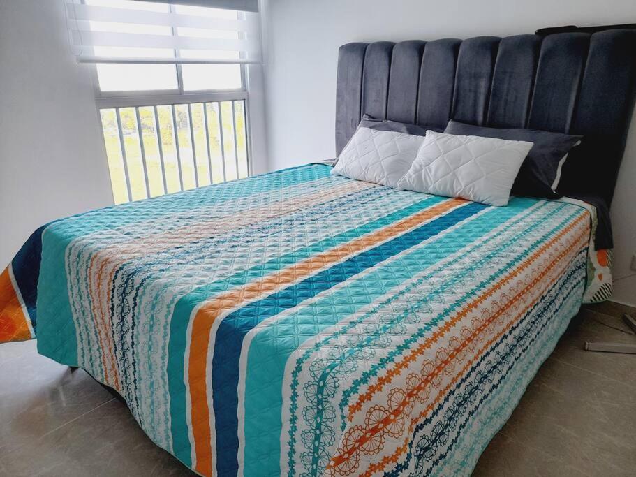 Un dormitorio con una cama con una colcha colorida. en Hermoso apartamento con piscina ubicado cerca a los principales centros comerciales, en Ibagué