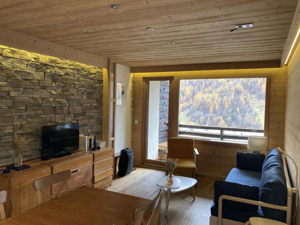 un salon avec un canapé bleu et une grande fenêtre dans l'établissement Appartement 2 Pièces + Coin Montagne pour 6 avec Parking et Wi-Fi - FR-1-762-20, à Saint-Chaffrey