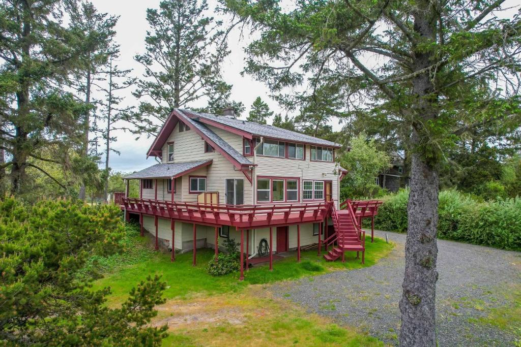 una casa grande con una terraza roja en el bosque en Cunningham Coop, en Seaside