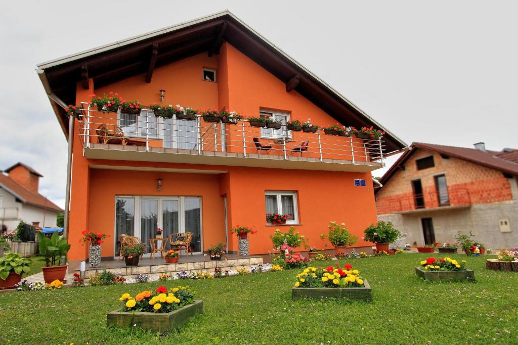 an orange house with flowers in front of it at Vila Julija - Apartment & rooms in Otočac