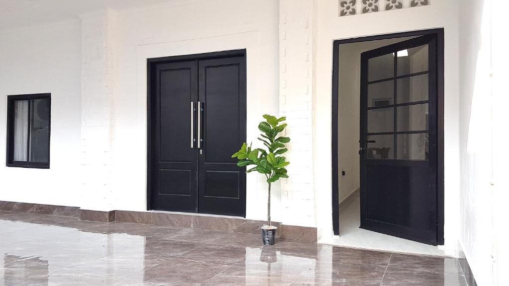 two black doors on a white building with a potted plant at Rumah Benhil, Bendungan Hilir - Senayan in Jakarta