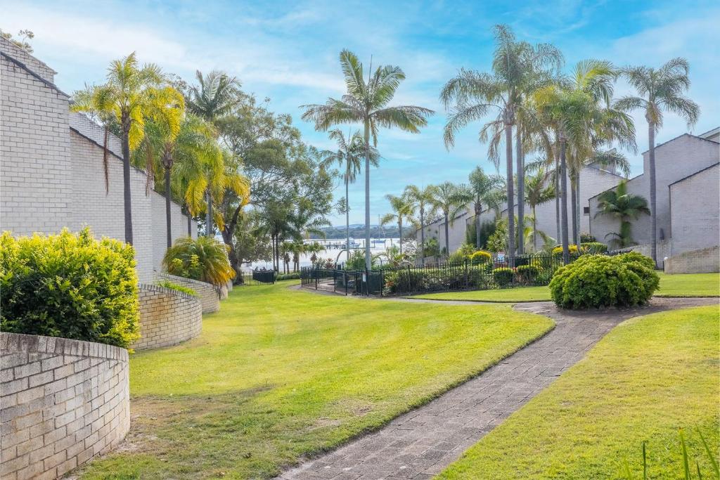 a walkway through a park with palm trees at The Moorings 18 4 Cromarty Rd Waterfront, Pool, Wifi & AirCon in Soldiers Point
