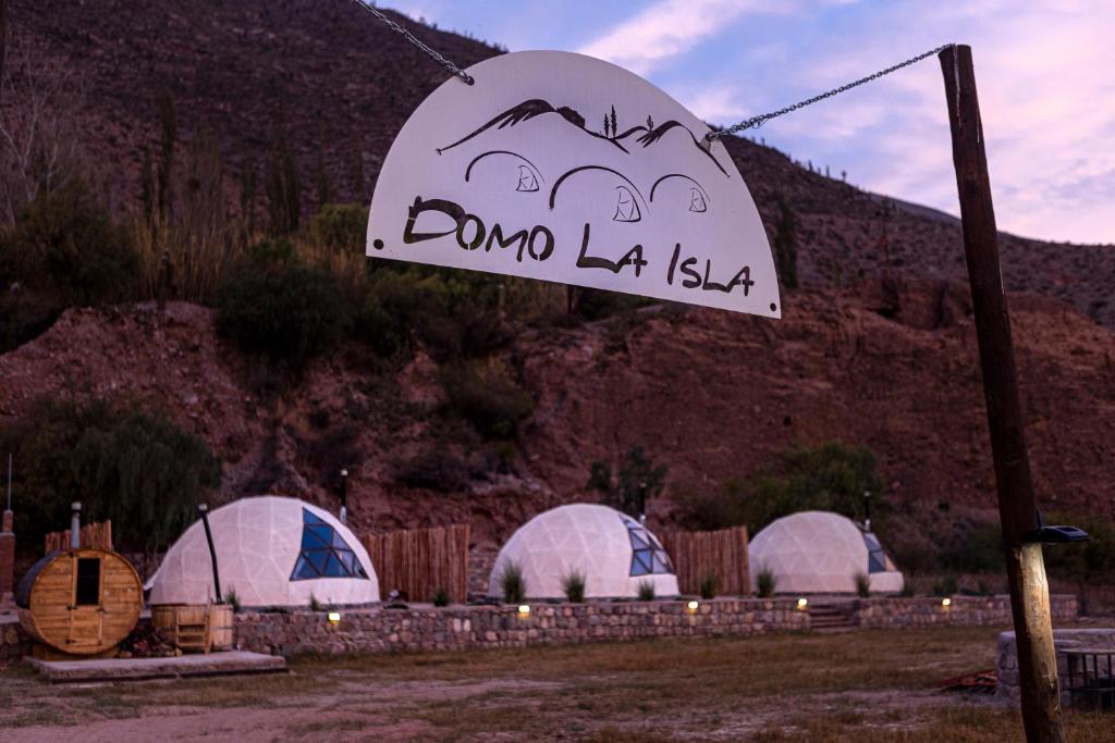 un groupe de dômes dans un champ avec un signe dans l'établissement Domo La Isla, à Tilcara