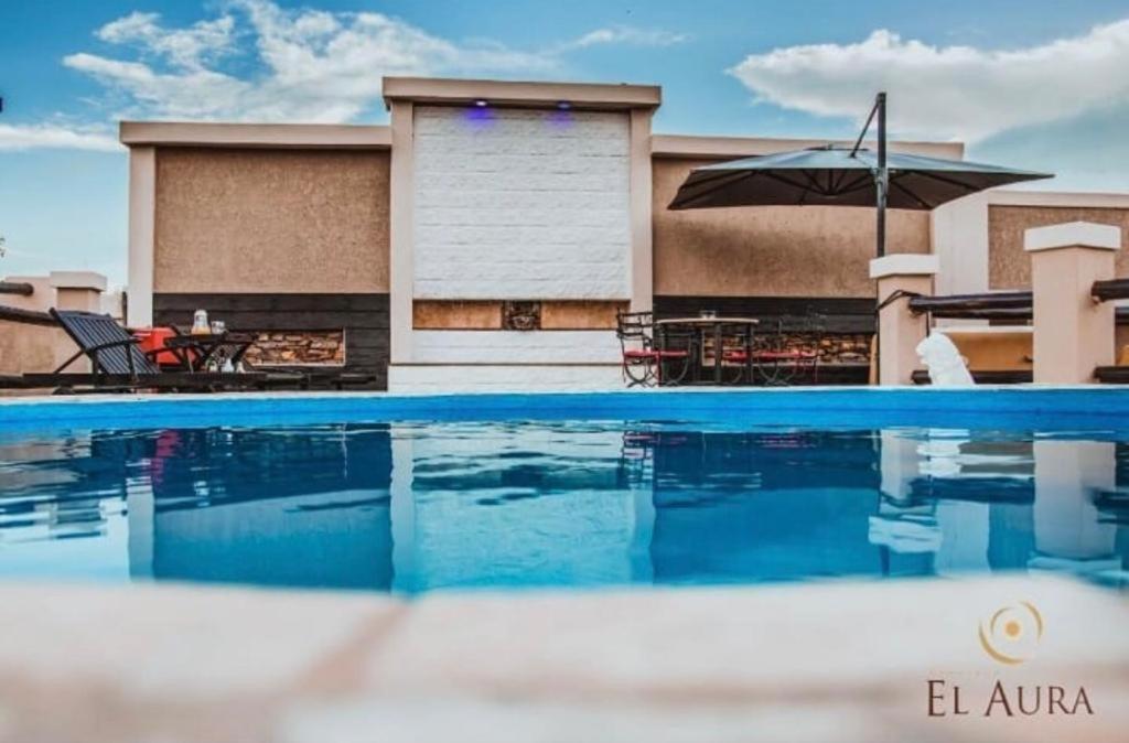 a swimming pool with a table and an umbrella at El Aura l Complejo de apartamentos amoblados in Villa Krause