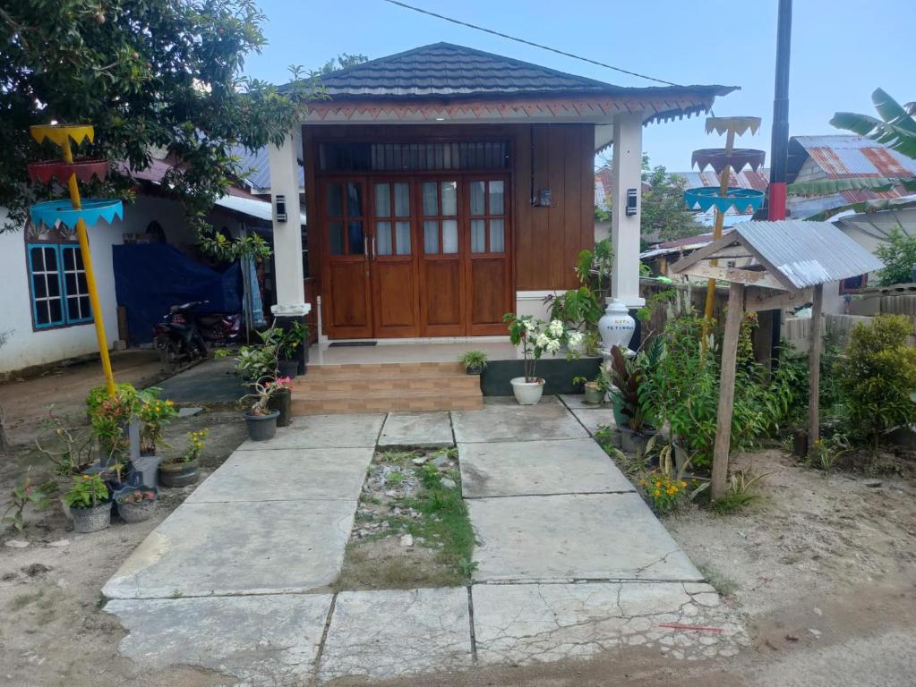 Homestay Erna Tanjong Tinggi في Pasarbaru: منزل صغير مع باب خشبي