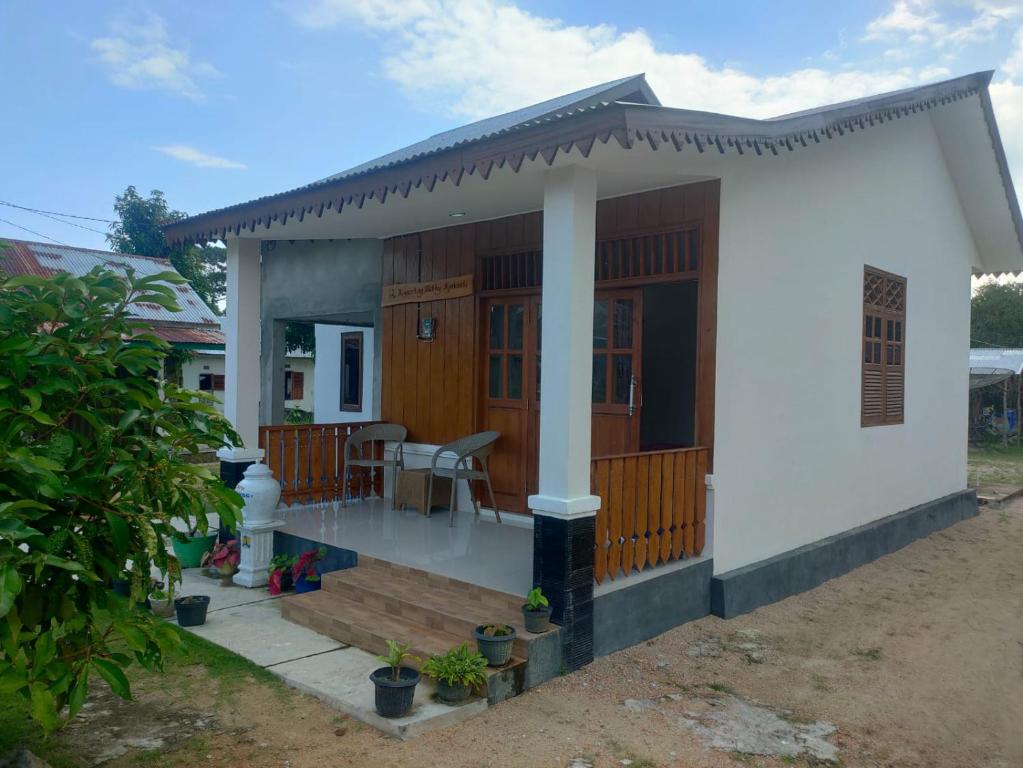 Homestay Melty Aprianti Tanjong Tinggi في Pasarbaru: منزل أبيض صغير مع شرفة