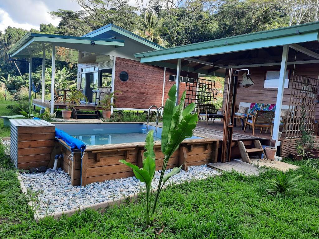 una casa y una piscina en el patio trasero con bañera de hidromasaje en Fare Juanita Piti en Opoa