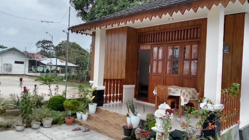 Homestay Suryati Tanjong Tinggi في Pasarbaru: منزل به باب خشبي ومجموعة من النباتات الفخارية
