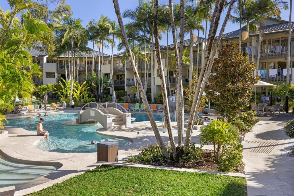 una piscina en un complejo con una persona en el agua en The Isla on Hastings, en Noosa Heads