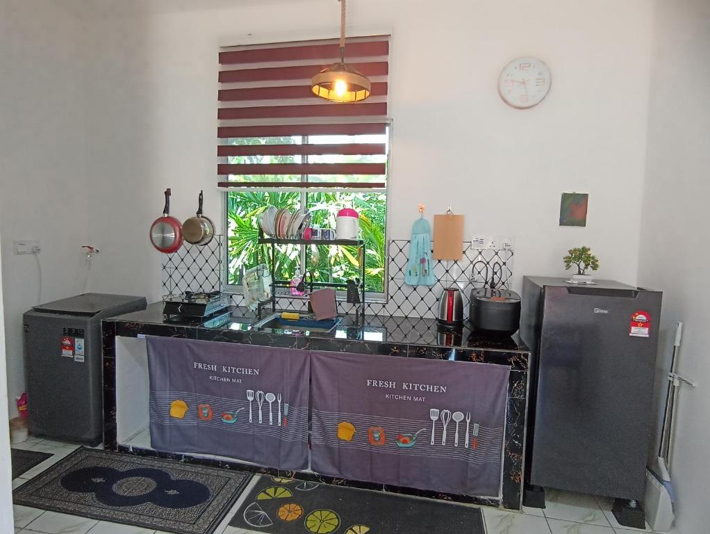 een keuken met een tafel en 2 koelkasten bij Haji Ineng Homestay- Guest House in Kota Samarahan