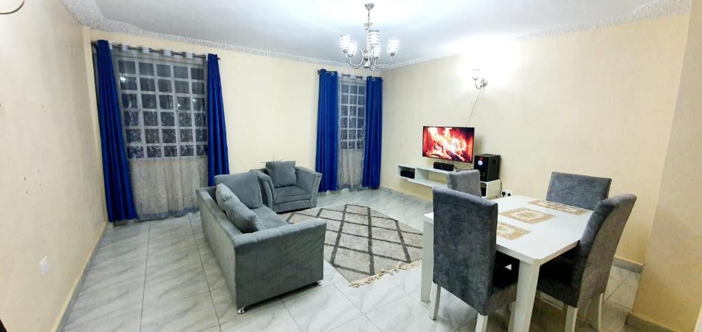 a living room with a table and chairs and a television at Tai Homes in Eldoret