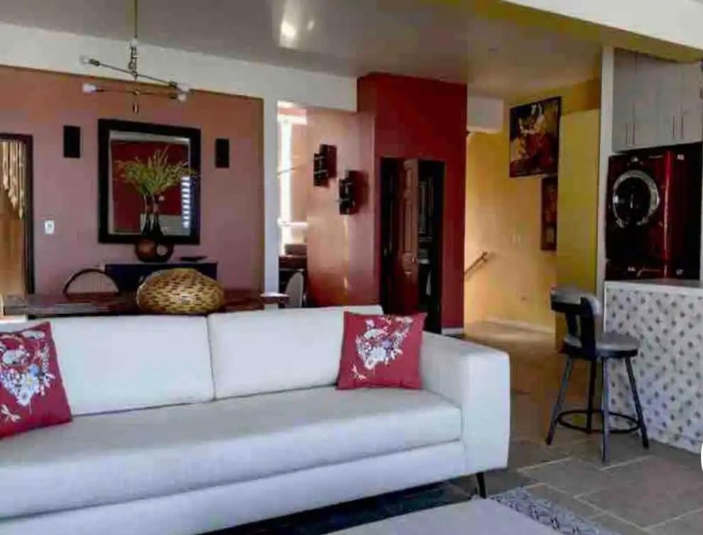 sala de estar con sofá blanco y almohadas rojas en las palmas en Ensenada
