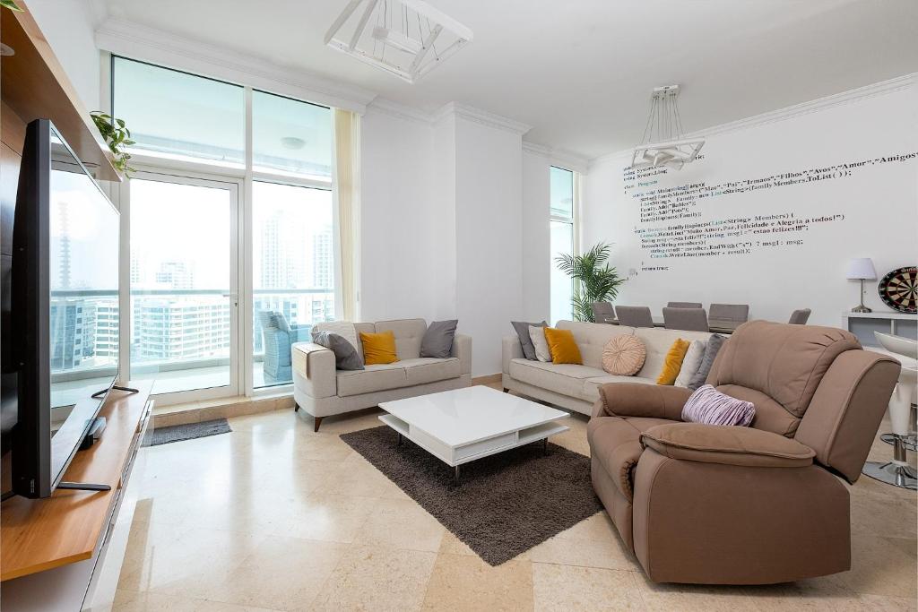 a living room with two couches and a tv at Dubai Marina 2BR Beach Oasis in Dubai