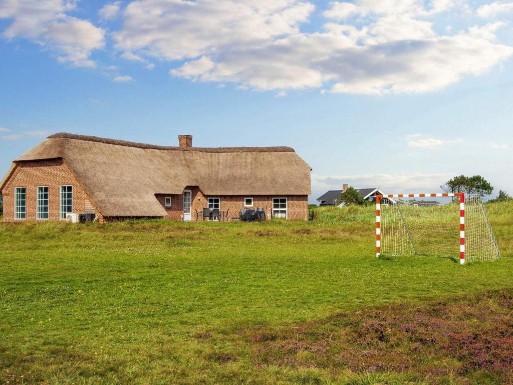 an old house with a gambrel roof in a field at 12 person holiday home in Ringk bing in Søndervig