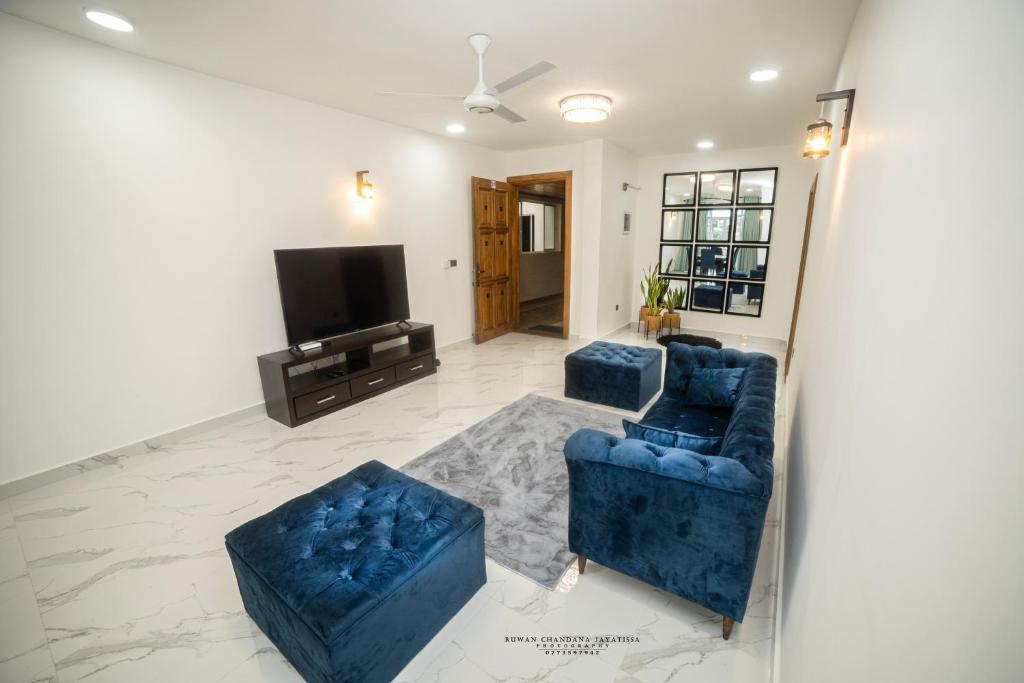 Sala de estar con 2 sofás azules y TV en BNB RESIDENCE MOUNT LAVINIA 1, en Mount Lavinia