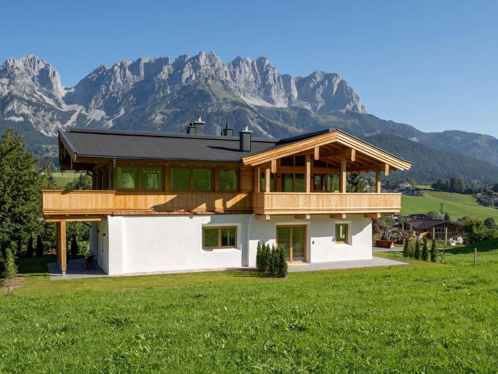 a house in a field with mountains in the background at Das Kaiserwohl Chalet in Going