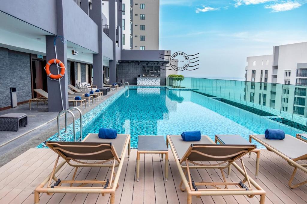 een zwembad op het dak van een gebouw met stoelen en een zwembad bij Jazz Service Suite Penang in Tanjong Tokong