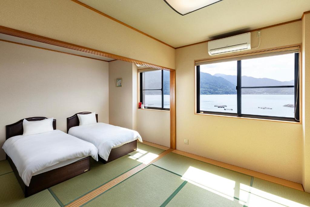 Rakusansui Villa في Itoshima: غرفة نوم بسريرين ونافذة