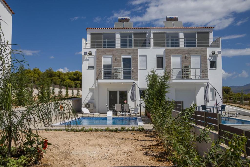 una casa bianca con una piscina di fronte di Enchanted Sunlit Villa Retreat a Isthmia